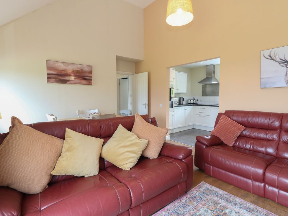A living room with sofas and a kitchen entrance at Sunset Cottage in Craignure, Isle Of Mull