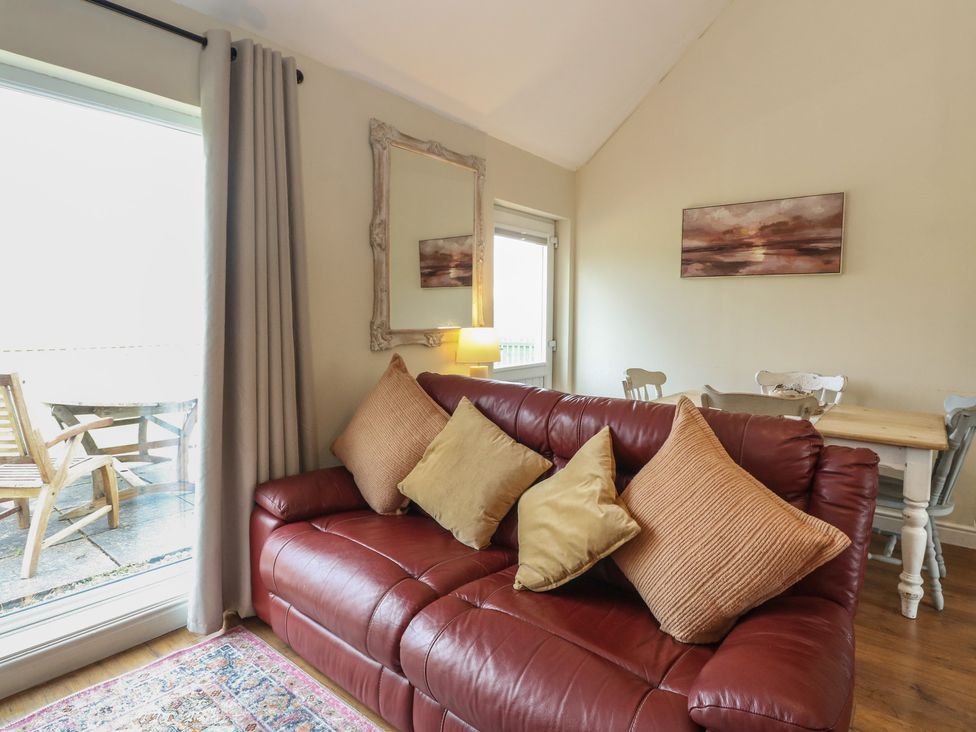 A living room with a sofa and dining area at Sunset Cottage in Craignure, Isle Of Mull