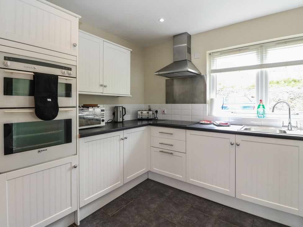 A kitchen with an oven, microwave, and sink at Sunset Cottage in Craignure, Isle Of Mull