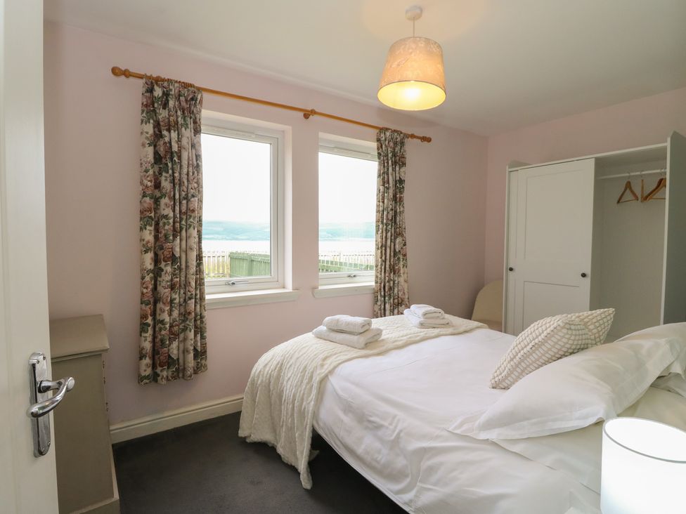 A bedroom with a bed and windows at Sunset Cottage, Craignure, Isle Of Mull