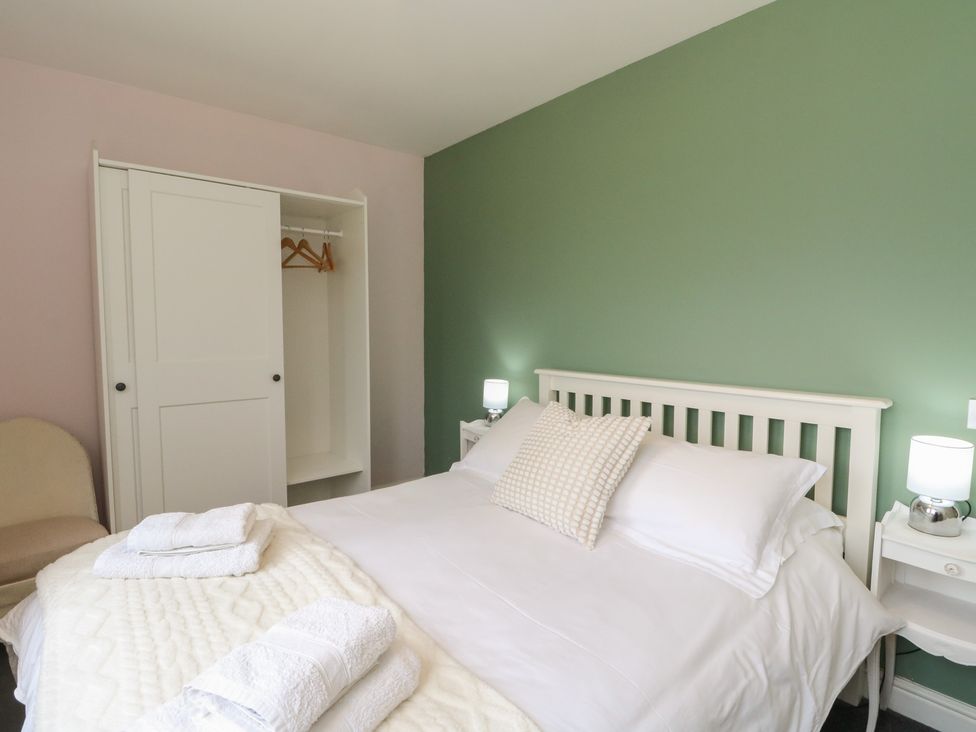 A bedroom with a bed, wardrobe, and nightstand at Sunset Cottage, Craignure, Isle Of Mull