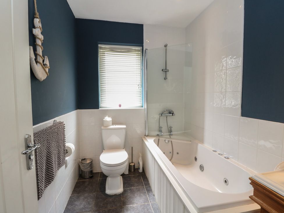 A bathroom with a toilet, bathtub, sink, and shower at Sunset Cottage, Craignure, Isle Of Mull