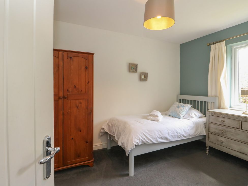 A bedroom with a bed and wardrobe at Sunset Cottage in Craignure, Isle Of Mull