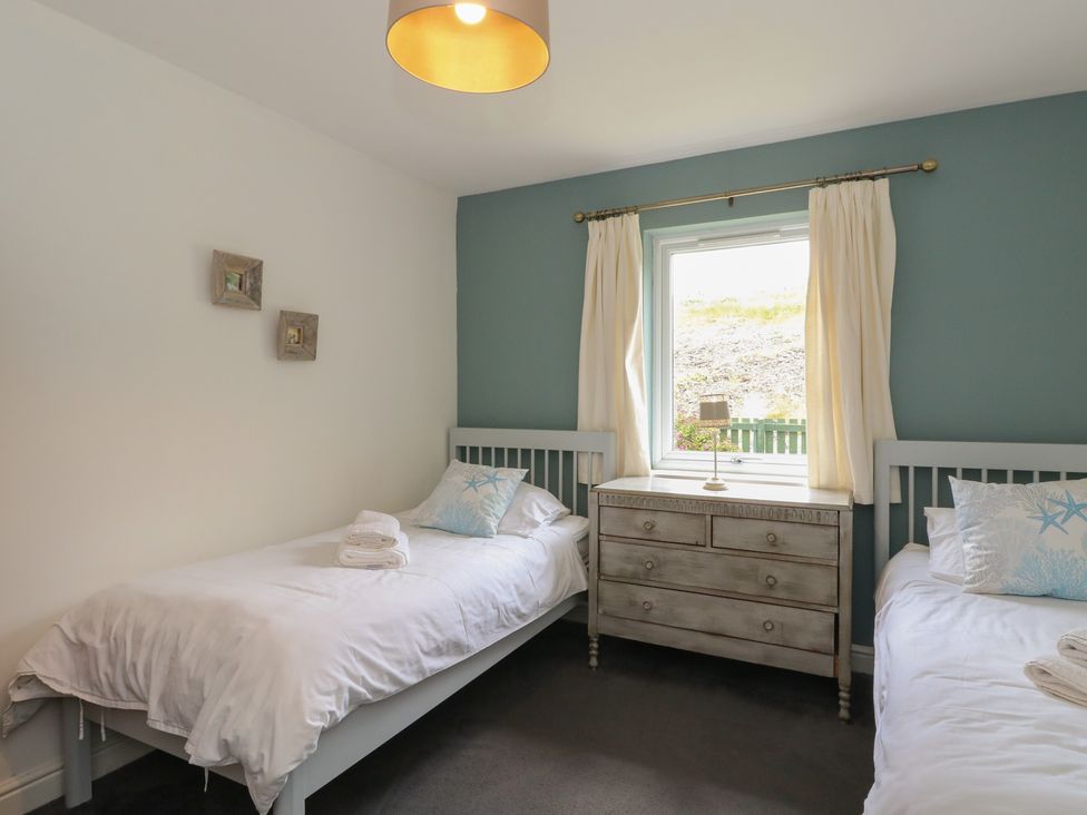 A bedroom with two beds and a nightstand at Sunset Cottage, Craignure, Isle Of Mull