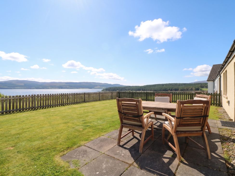 A garden with a table and chairs overlooking a view at Sunset Cottage in Craignure, Isle Of Mull