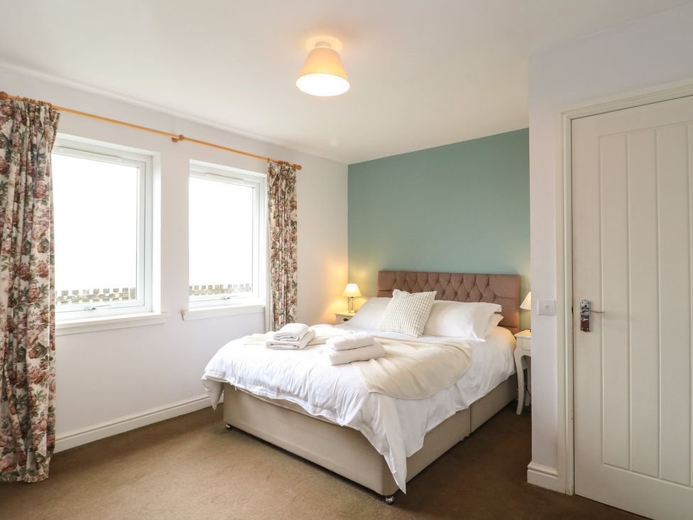 A bedroom with a bed and curtains at Starfish Cottage, Craignure, Isle Of Mull