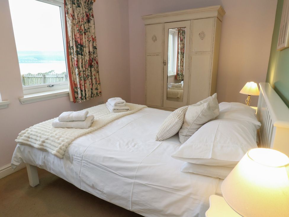 A bedroom with a bed and wardrobe at Driftwood Cottage, Craignure, Isle Of Mull