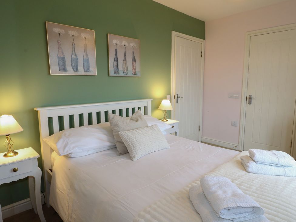 A bedroom with a bed and wall art at Driftwood Cottage, Craignure, Isle Of Mull
