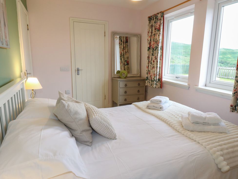A bedroom with a bed and dresser at Driftwood Cottage, Craignure, Isle Of Mull