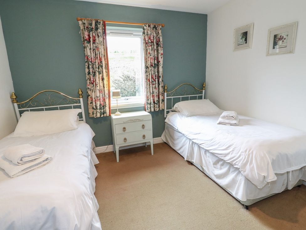 A bedroom with two beds and a window at Driftwood Cottage, Craignure, Isle Of Mull
