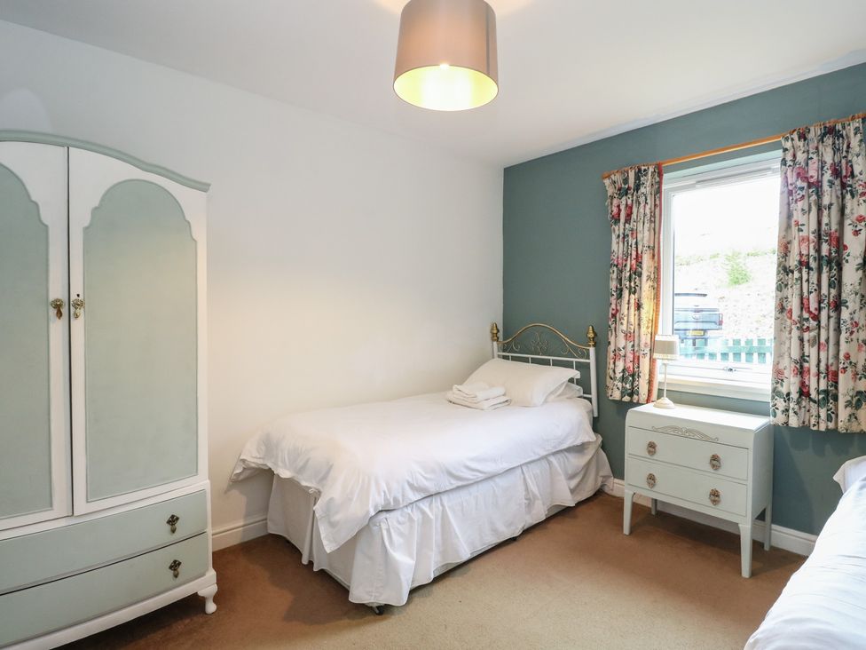 A bedroom with a bed and wardrobe at Driftwood Cottage Craignure, Isle Of Mull