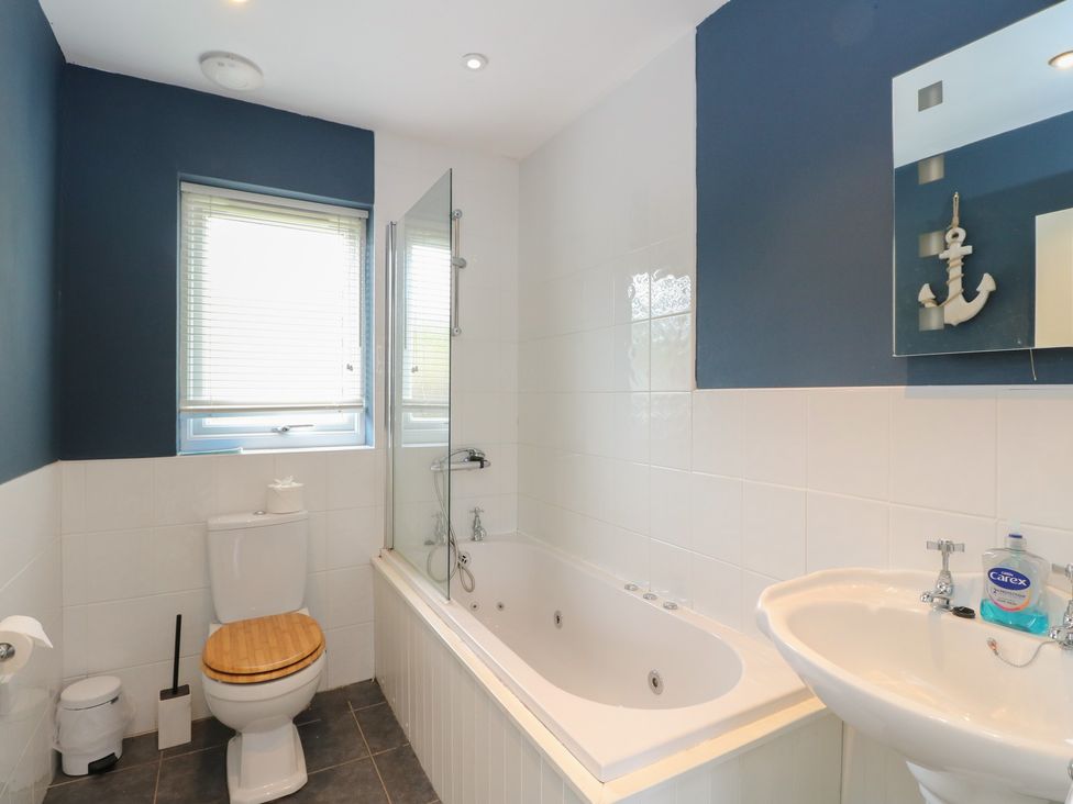 A bathroom with a bath tub, toilet and sink at Driftwood Cottage, Craignure, Isle Of Mull