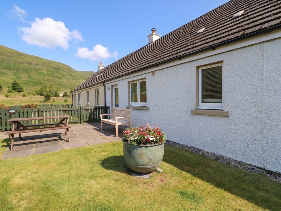 An outdoor area with a house, patio furniture and a flower pot at Driftwood Cottage, Craignure, Isle Of Mull