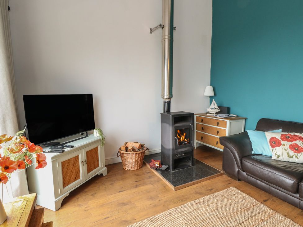 A living room with a wood burner stove and television at Poppies Cottage Craignure, Isle Of Mull