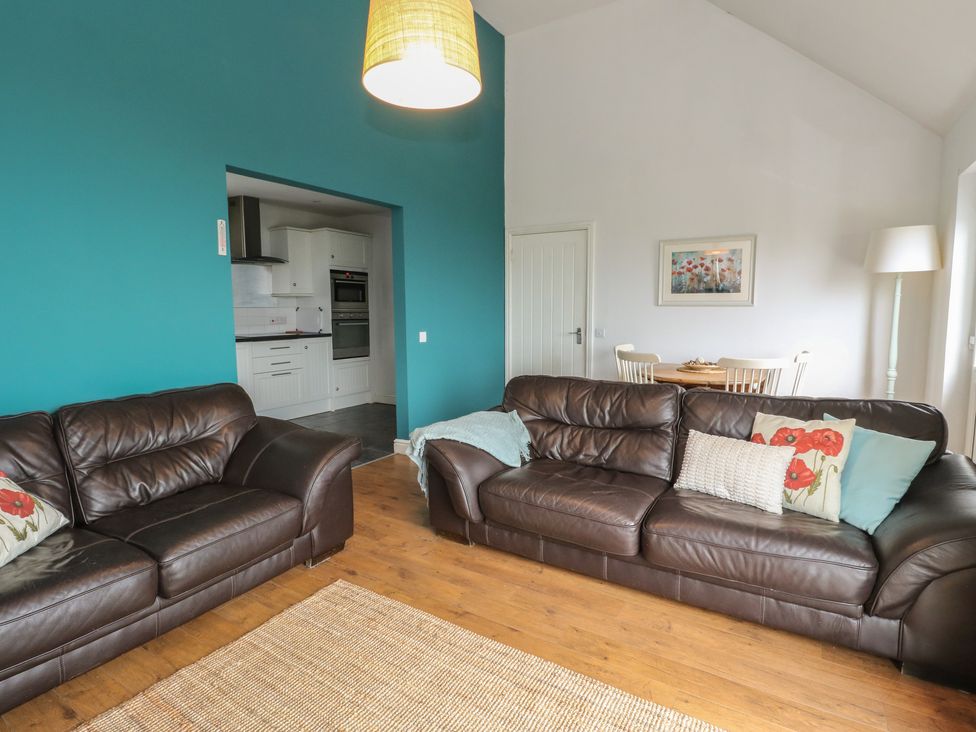 A living room with sofas and a dining area at Poppies Cottage, Craignure, Isle Of Mull