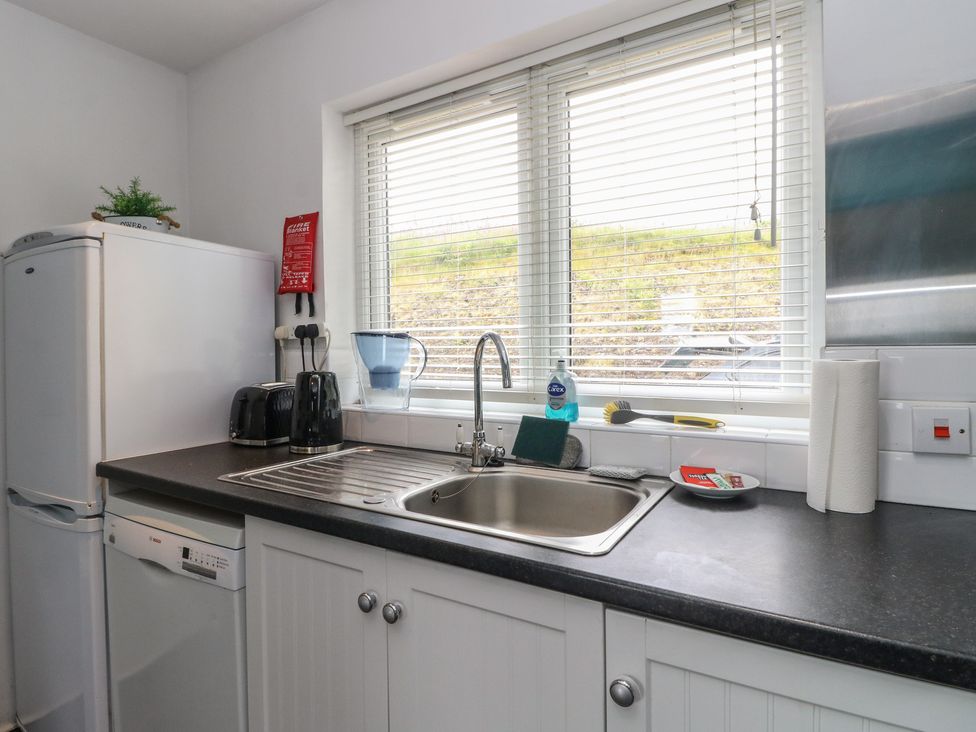 A kitchen with a sink and refrigerator at Poppies Cottage in Craignure, Isle Of Mull