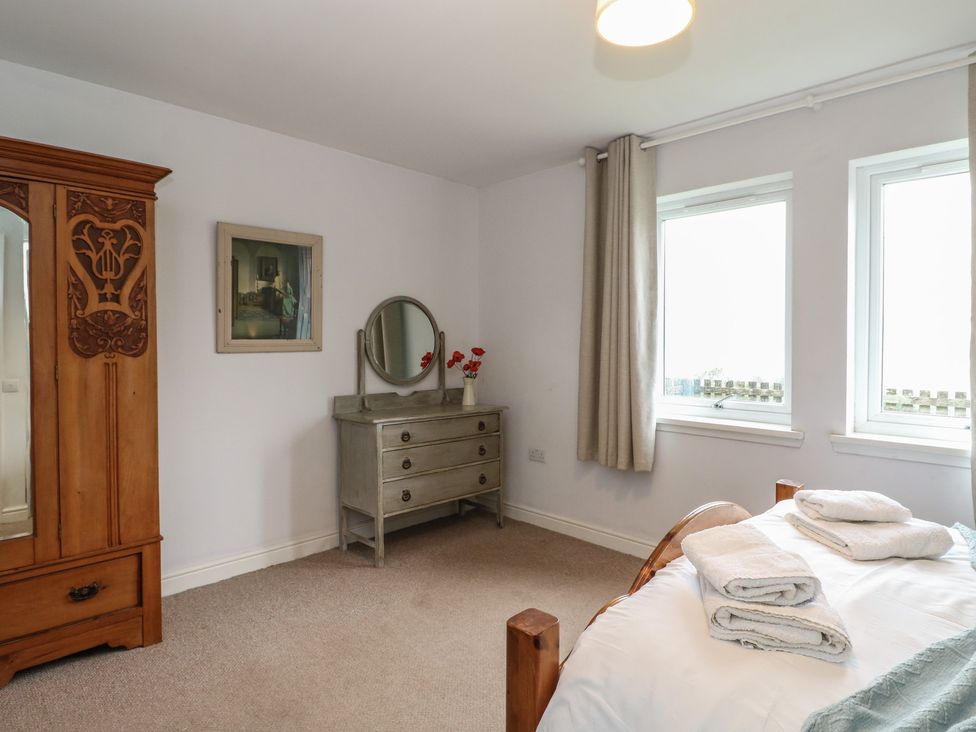 A bedroom with a wardrobe, mirror and dresser at Poppies Cottage, Craignure, Isle Of Mull
