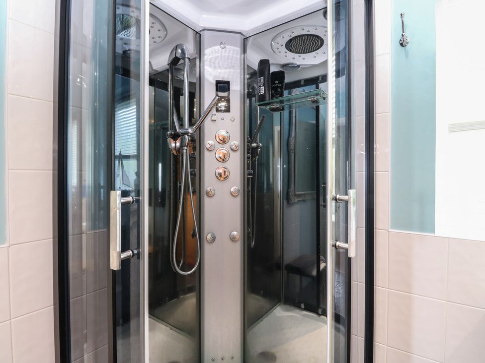 A shower enclosure with control panel and glass door at Poppies Cottage in Craignure, Isle Of Mull