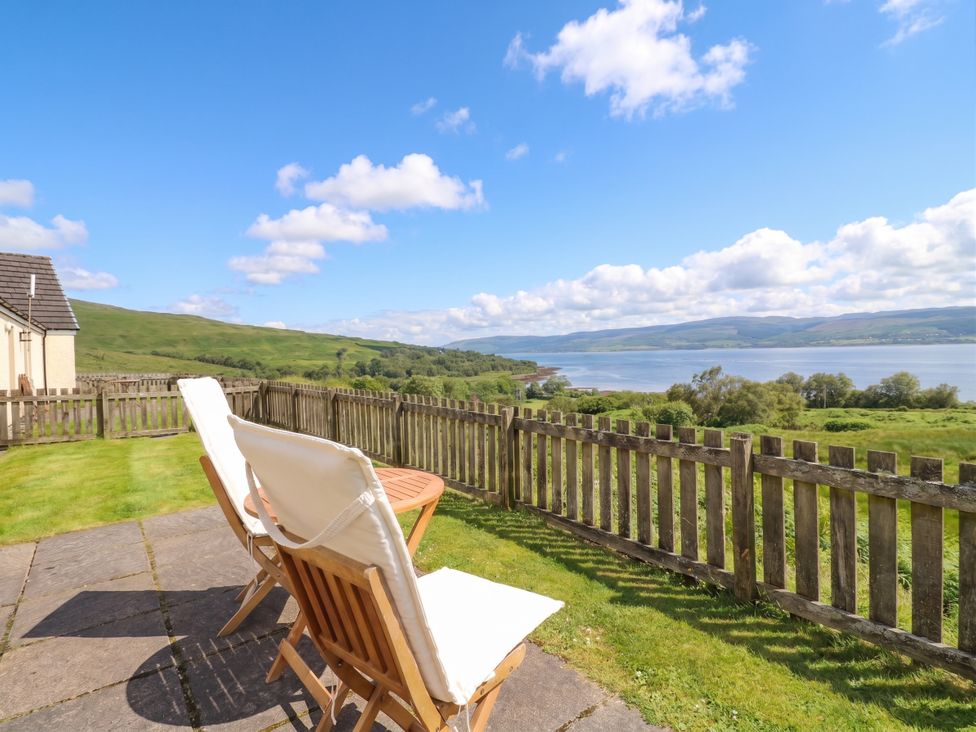 An outdoor area with deck chairs and a table at Poppies Cottage Craignure, Isle Of Mull