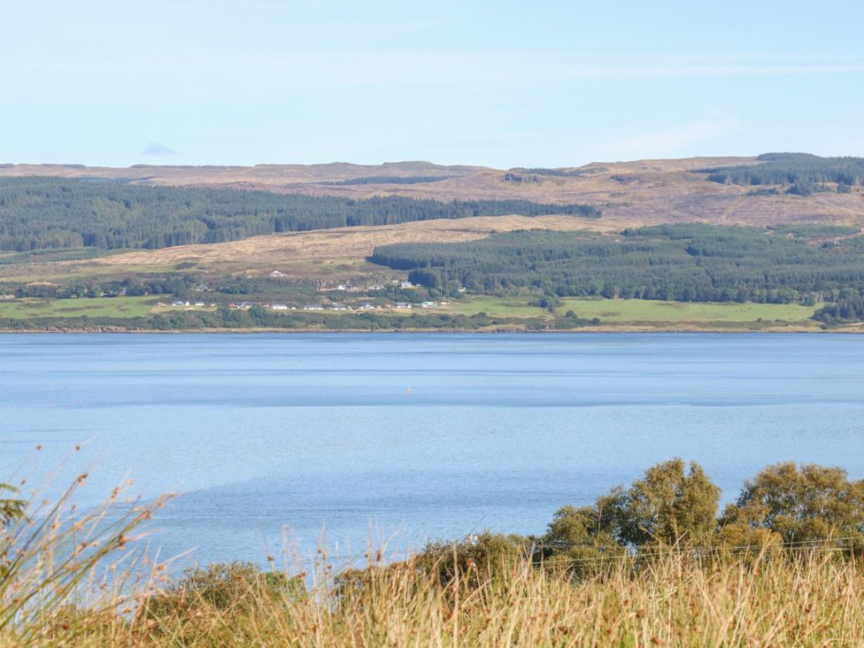 A view of trees and houses across the water at Poppies Cottage Craignure, Isle Of Mull