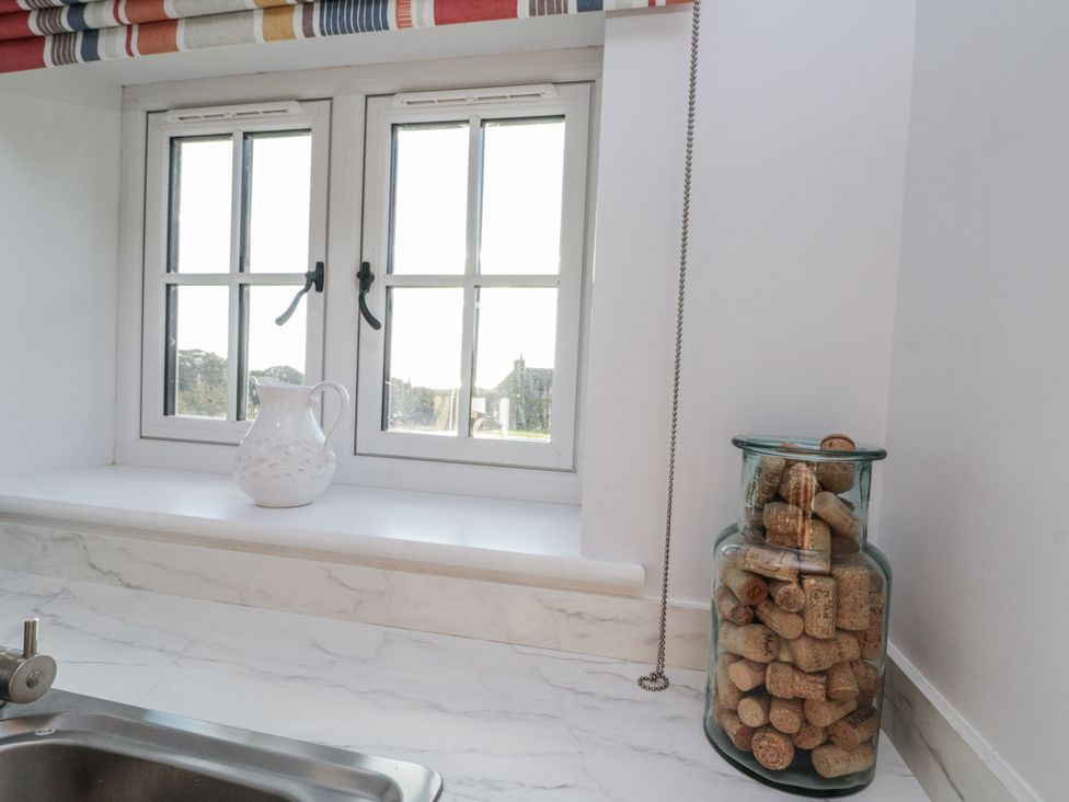 A kitchen with a sink, pitcher, cork jar, and windows at Croft View in Fylingthorpe near Robin Hood's Bay