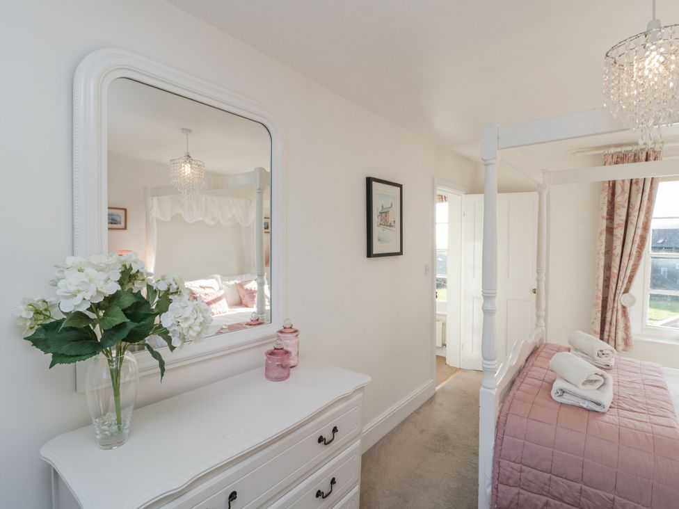 A bedroom with a mirror and a four-poster bed at Croft View in Fylingthorpe near Robin Hood's Bay