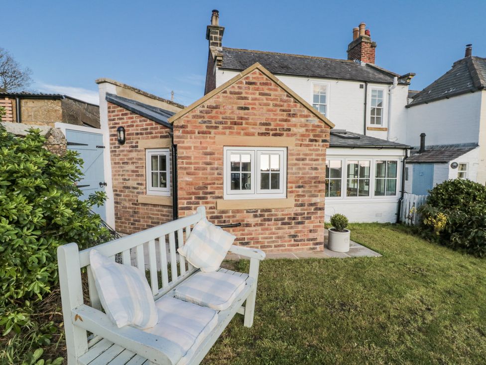 A garden with a bench and a brick cottage at Croft View in Fylingthorpe near Robin Hood's Bay