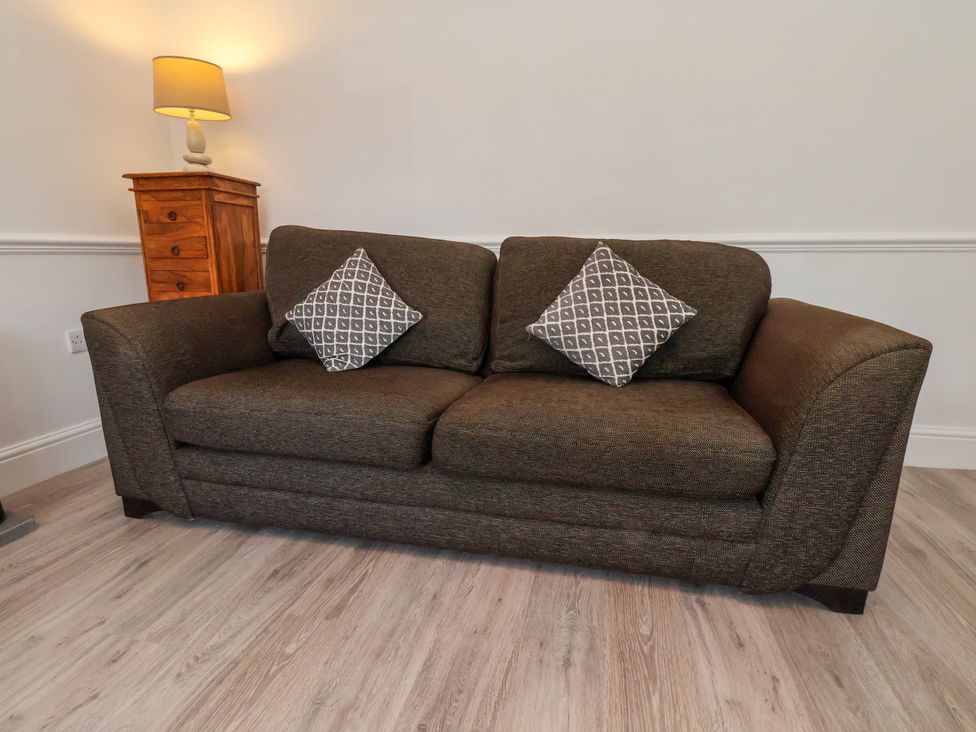A sofa with cushions and a lamp in a living room at 1 Roxby Terrace Thornton-le-Dale