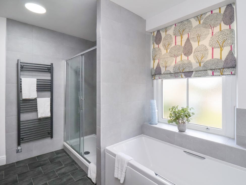 A bathroom with a bathtub, shower, and towel rack at 1 Roxby Terrace Thornton-le-Dale