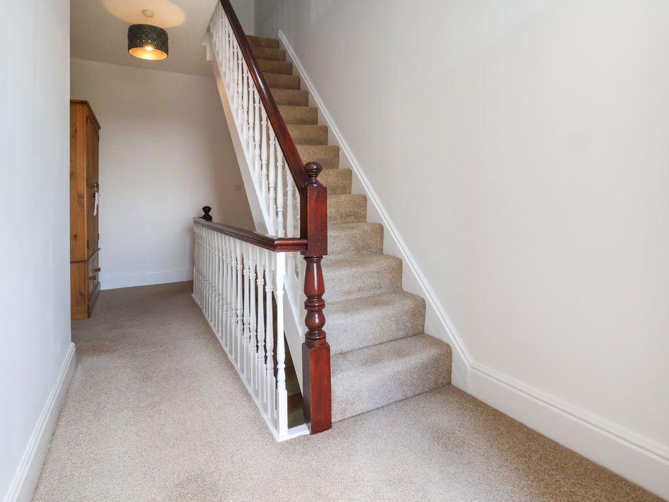 A hallway with a staircase and a wooden cabinet at 1 Roxby Terrace in Thornton-le-Dale