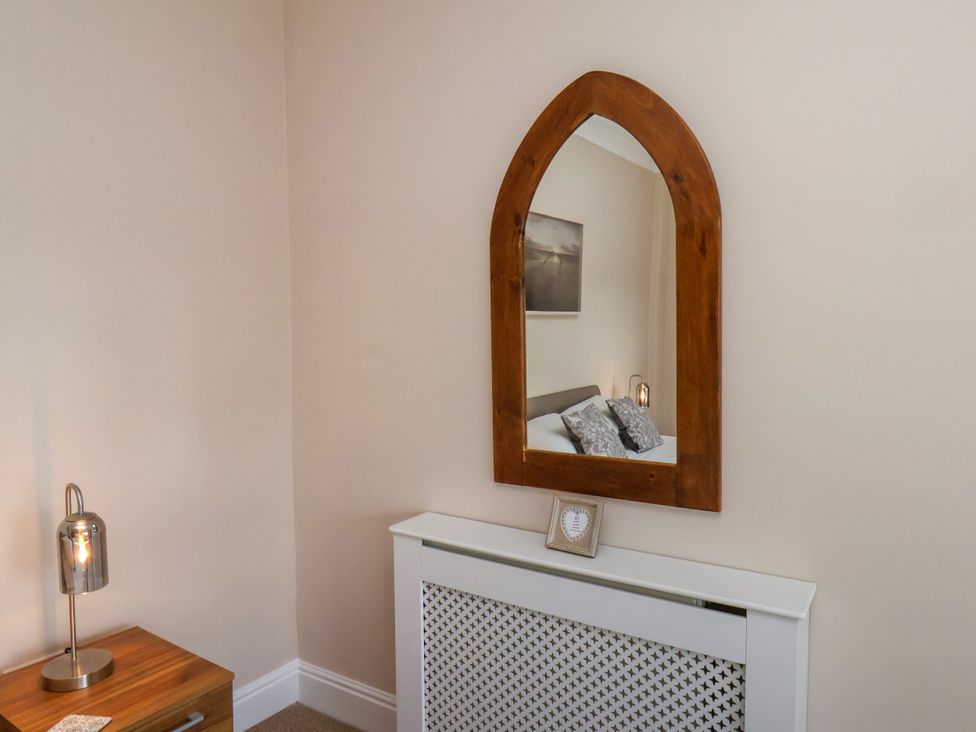 A bedroom with a mirror and a lamp at 1 Roxby Terrace in Thornton-le-Dale