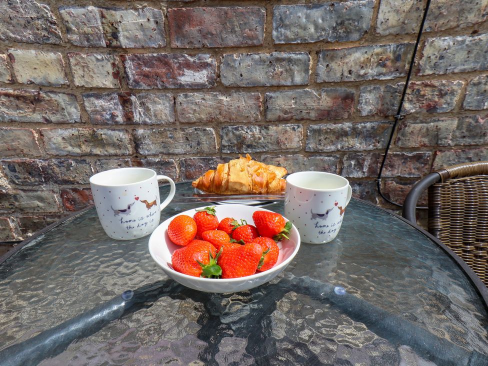 An outdoor dining area with cups, strawberries, and a croissant at 1 Roxby Terrace Thornton-le-Dale
