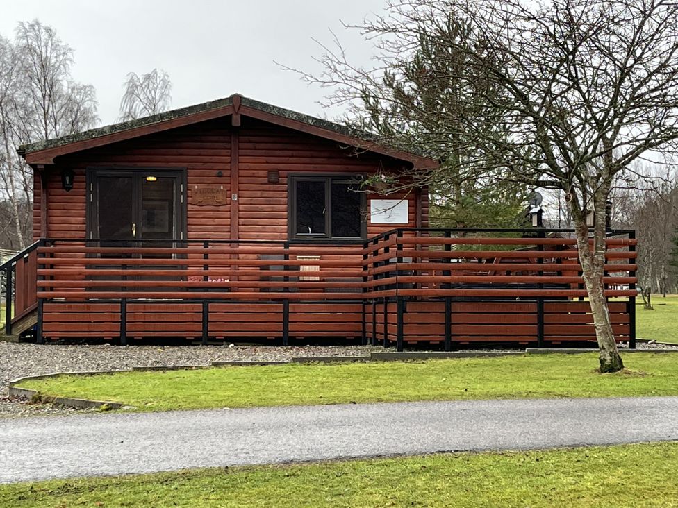 A cabin with a deck and sliding door at Wildcat Lodge in Newtonmore