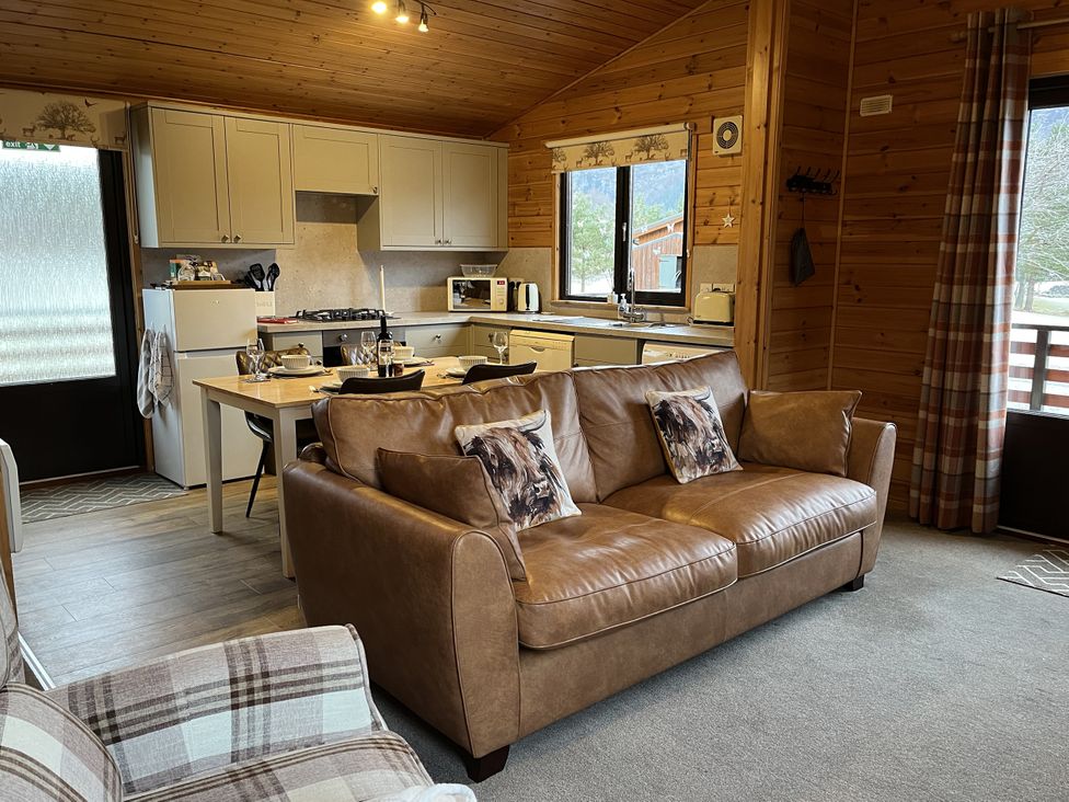 A living room with a kitchen area and dining table at Wildcat Lodge in Newtonmore