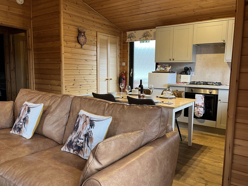 A kitchen area with a sofa and dining table at Wildcat Lodge in Newtonmore