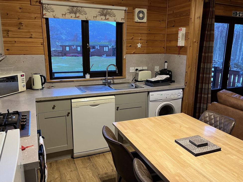 A kitchen with appliances and table at Wildcat Lodge in Newtonmore