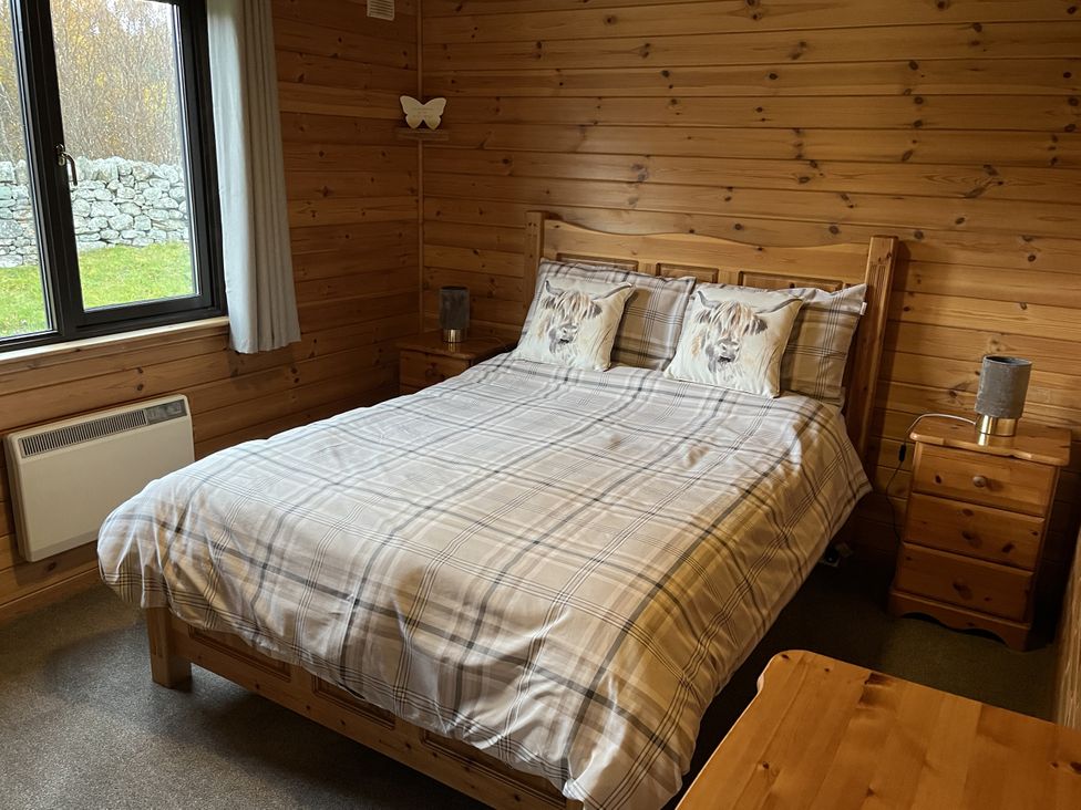 A bedroom with a bed and bedside tables at Wildcat Lodge in Newtonmore