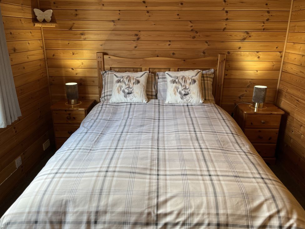 A bedroom with wooden walls and a bed at Wildcat Lodge in Newtonmore
