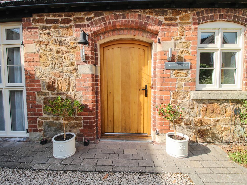 An entrance with a wooden door and plants at Swallows Cottage Harley near Much Wenlock