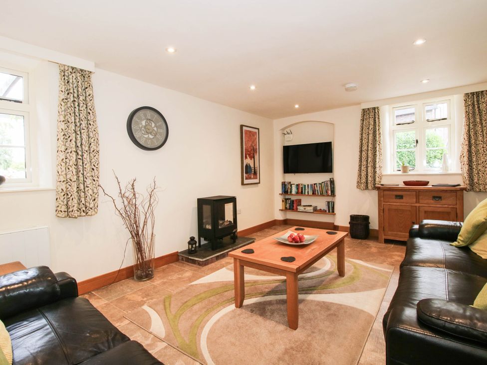 A living room with a fireplace and bookshelf at Swallows Cottage in Harley near Much Wenlock