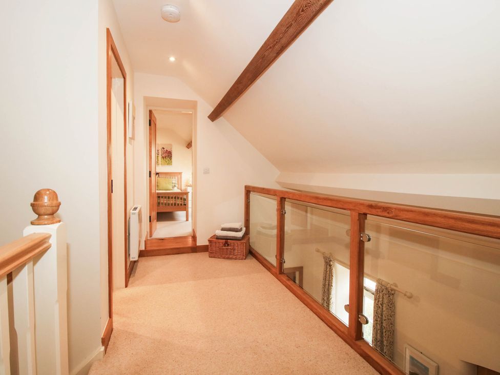 A hallway with wooden balustrade and doors at Swallows Cottage Harley near Much Wenlock