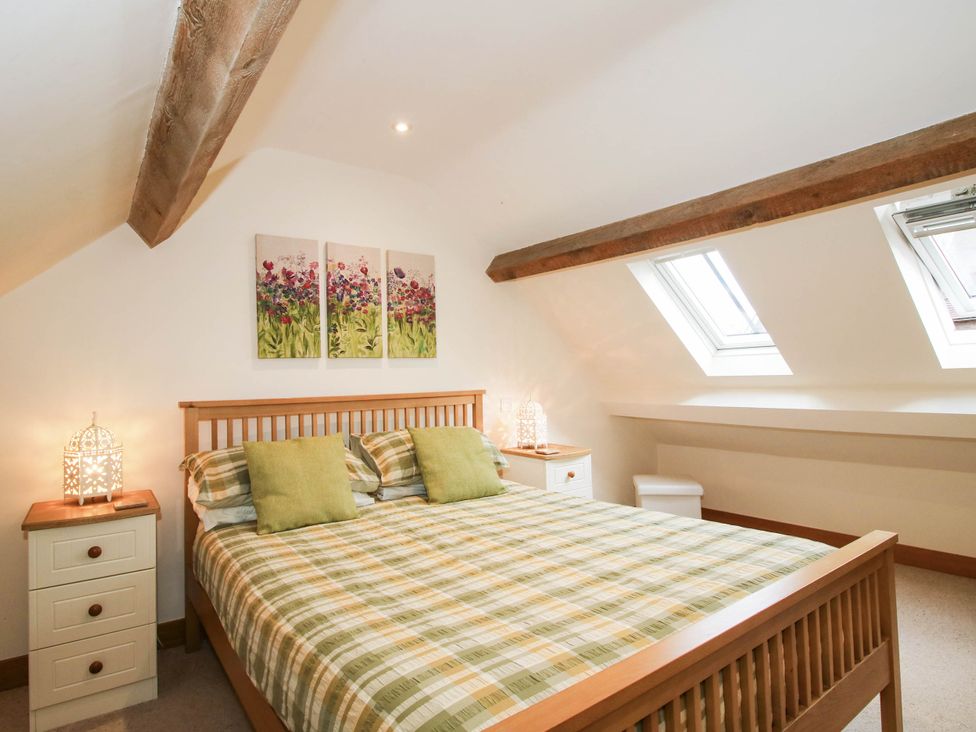 A bedroom with a bed and artwork on the wall at Swallows Cottage in Harley near Much Wenlock