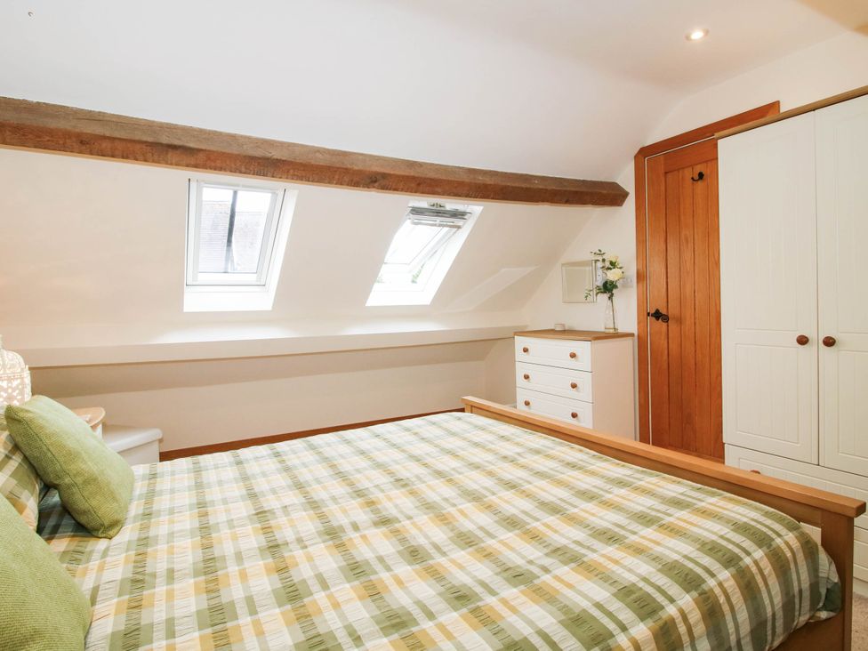 A bedroom with a bed and windows at Swallows Cottage Harley near Much Wenlock
