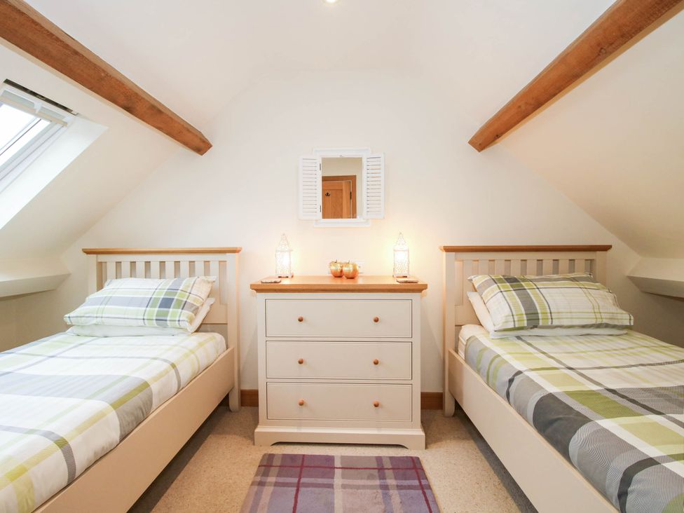 A bedroom with two single beds and a dresser at Swallows Cottage Harley near Much Wenlock
