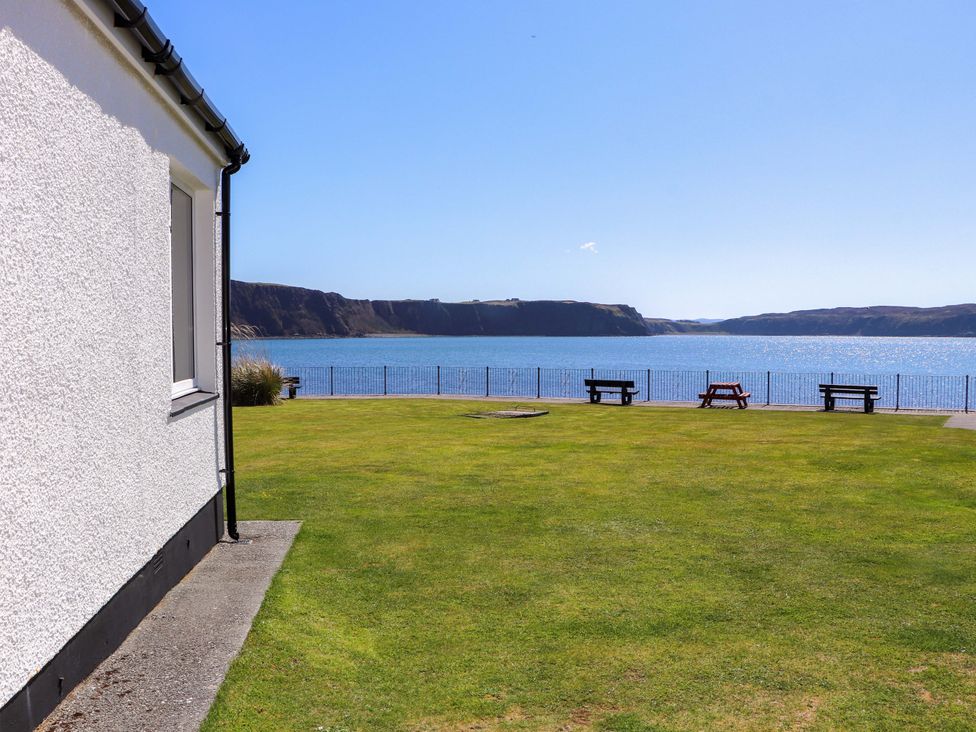 A view of the sea with benches and grass near Ceól na Mara in Uig