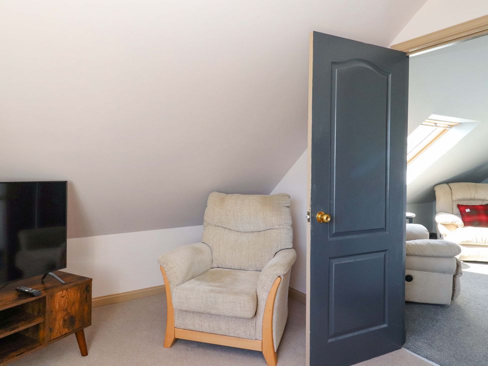 A living room with a chair and television at Ceól na Mara, Uig