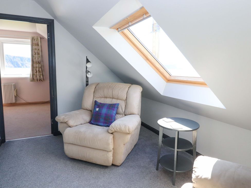 A loft with an armchair and a side table at Ceól na Mara in Uig
