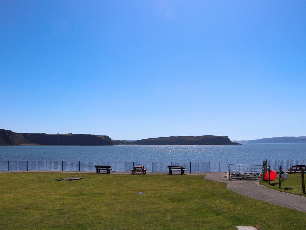 A view of the water with benches and a fence at Ceól na Mara Uig