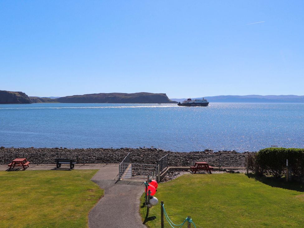 A view of water with a boat and benches at Ceól na Mara in Uig