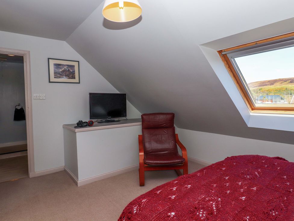 A bedroom with a television and a chair at Ceól na Mara in Uig